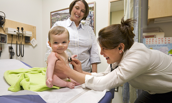 A physician listens to a smiling baby's heart as the mother watches A physician listens to a smiling baby's heart as the mother watches